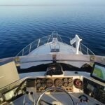 view from the fly bridge of a president 52 while on a yacht Delivery showing the instruments, helm and flat blue water in the distance