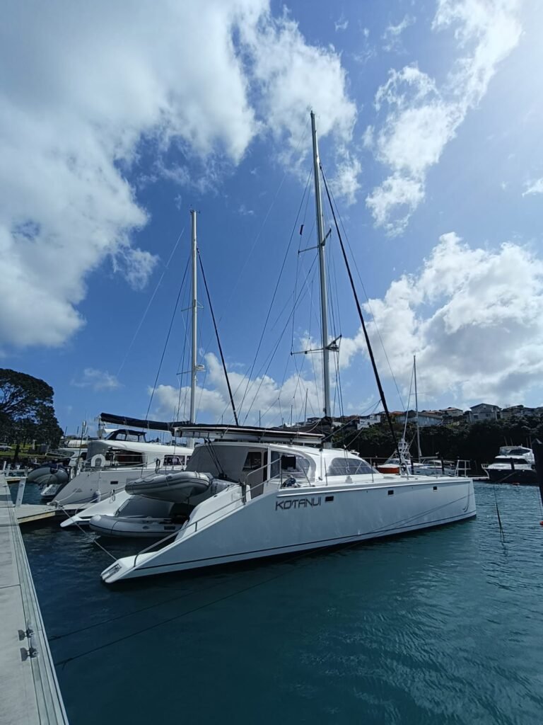 a greainger 52 white catamaran tied stern to the dock before a yacht delivery, you can see the starboard side and blue sky with white clods
