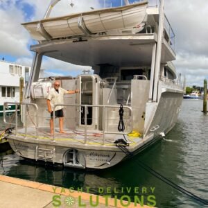 Circa 25 meter power Boat shown from the stern with the delivery Skipper standing on the aft section. the vessel is dark grey and spectacular